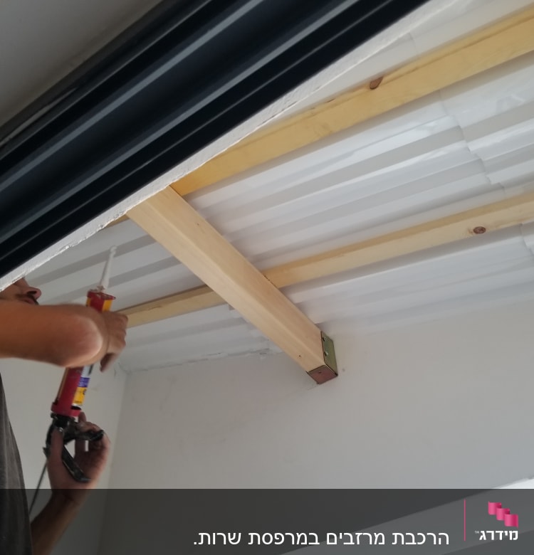 אדם משתמש באקדח סיליקון על גג עץ